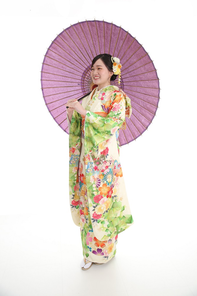 成人式の前撮りで緑の振袖を着て紫の番傘を持っている女性